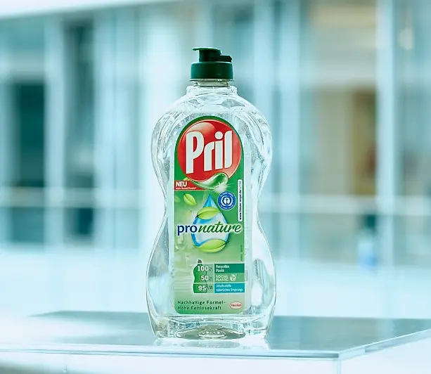 A bottle of the dishwashing product Pril Pro Nature standing on a transparent table.