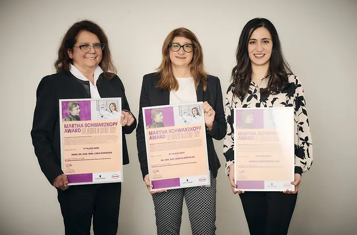 The three winners stand next to each other and hold their award certificates in their hands. 